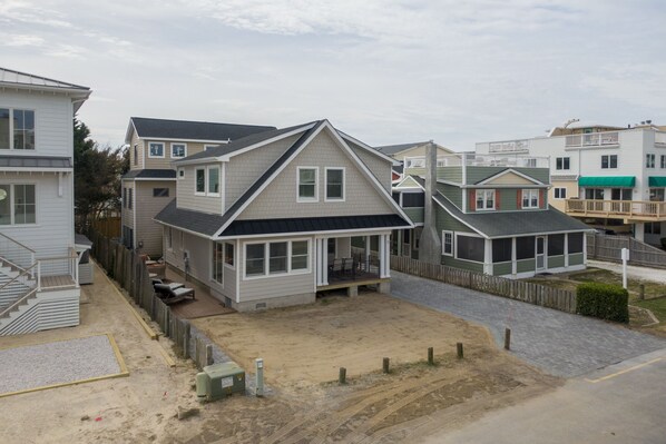 A residential area with houses featuring front porches, a sandy driveway, and a wooden fence. - RENOVATED IN 2024, OCEAN BLOCK CHARMER - 12 CLAYTON ST, DEWEY BEACH, DE (Dewey Beach)