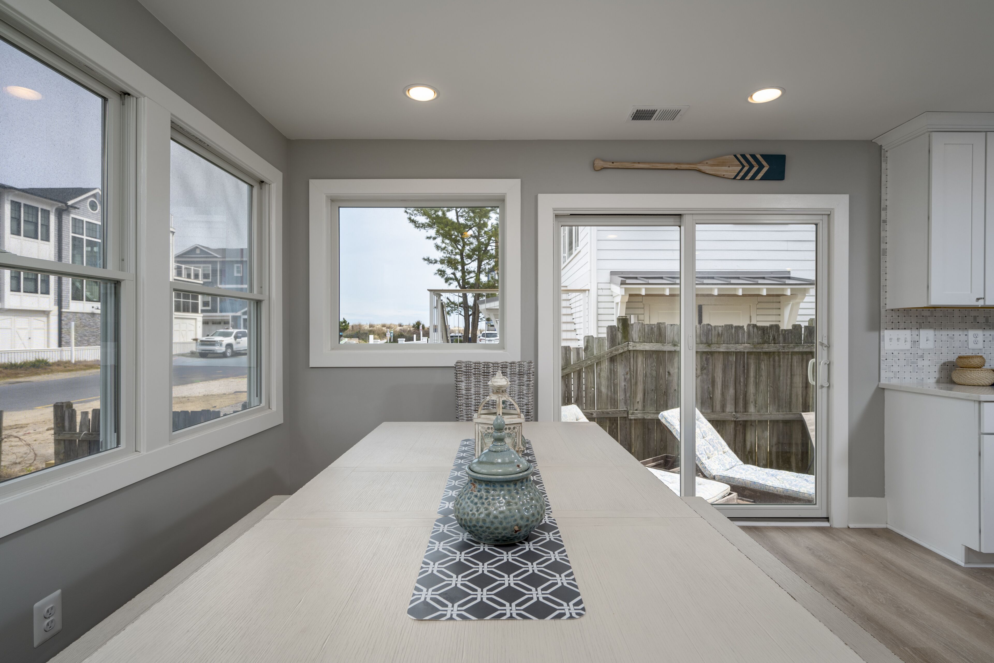 A modern kitchen with a large island, white cabinets, and a view of the outside.