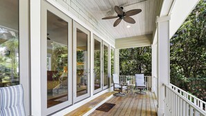 Eine überdachte Veranda mit Deckenventilator, Holzboden und einer Bank.