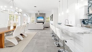 A modern kitchen with white cabinetry, a marble countertop, and a built-in oven.