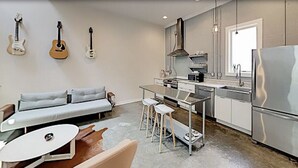 Una cocina moderna con comedor, sofá y guitarras colgadas en la pared.