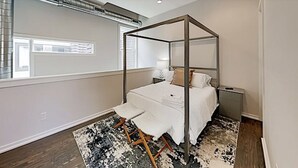 Un dormitorio moderno con una cama con dosel, una mesita de noche y un amplio ventanal.