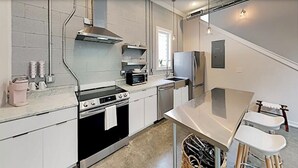 Cocina moderna con estufa, horno, microondas y refrigerador. Incluye un lavaplatos y una ventana que proporciona luz natural.