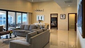 Una habitación de hotel moderna con un sofá grande, una zona de comedor y vistas al exterior del edificio.