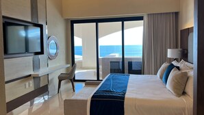 Una habitación de hotel moderna con una cama grande, televisión, escritorio y vistas al océano.