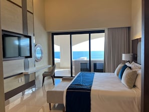 Une chambre d’hôtel moderne dotée d’un grand lit, d’une télévision, d’un bureau et offrant une vue sur l’océan.