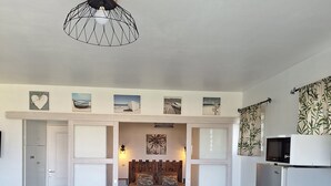 A modern living room with a round table, a sofa, a kitchen area with a refrigerator, and a dining area. - L'R2 LA VILLA MELISSA T2 APARTMENT WITH POOL 150 M FROM THE BEACH. (Les Trois-Îlets)