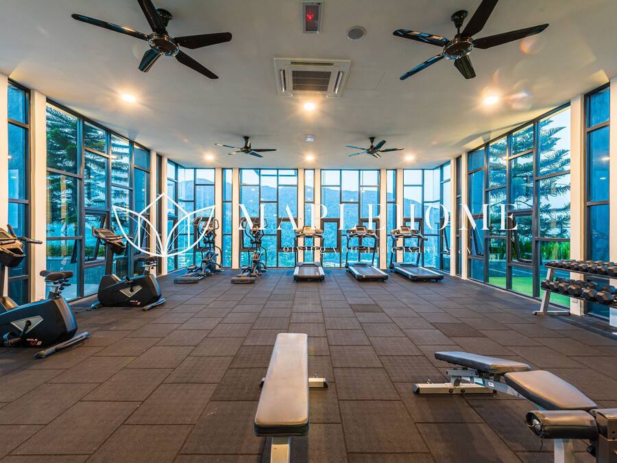 A gym with exercise equipment, large windows, and ceiling fans.