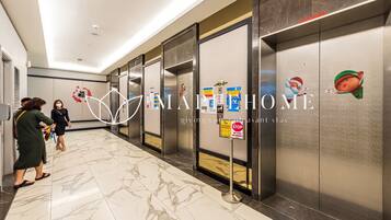 A hotel corridor with marble flooring, elevators, and a 'No Smoking' sign.