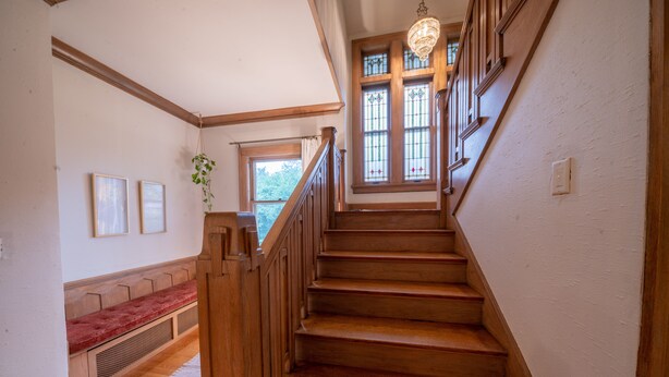 Una escalera de madera con un banco rojo y una planta colgante.