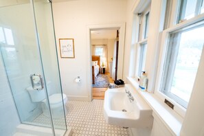 Une salle de bain avec une douche à parois de verre, un lavabo et une fenêtre.
