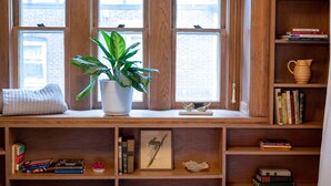 Un escritorio de madera con una planta en maceta, libros y un cuadro enmarcado.