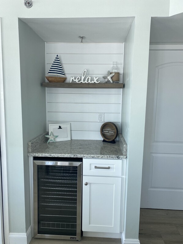 A kitchen with a built-in dishwasher, a wooden shelf with decorative items, and a 'relax' sign. - Completely renovated in Jan 2022! Free beach service! (Fort Walton Beach)