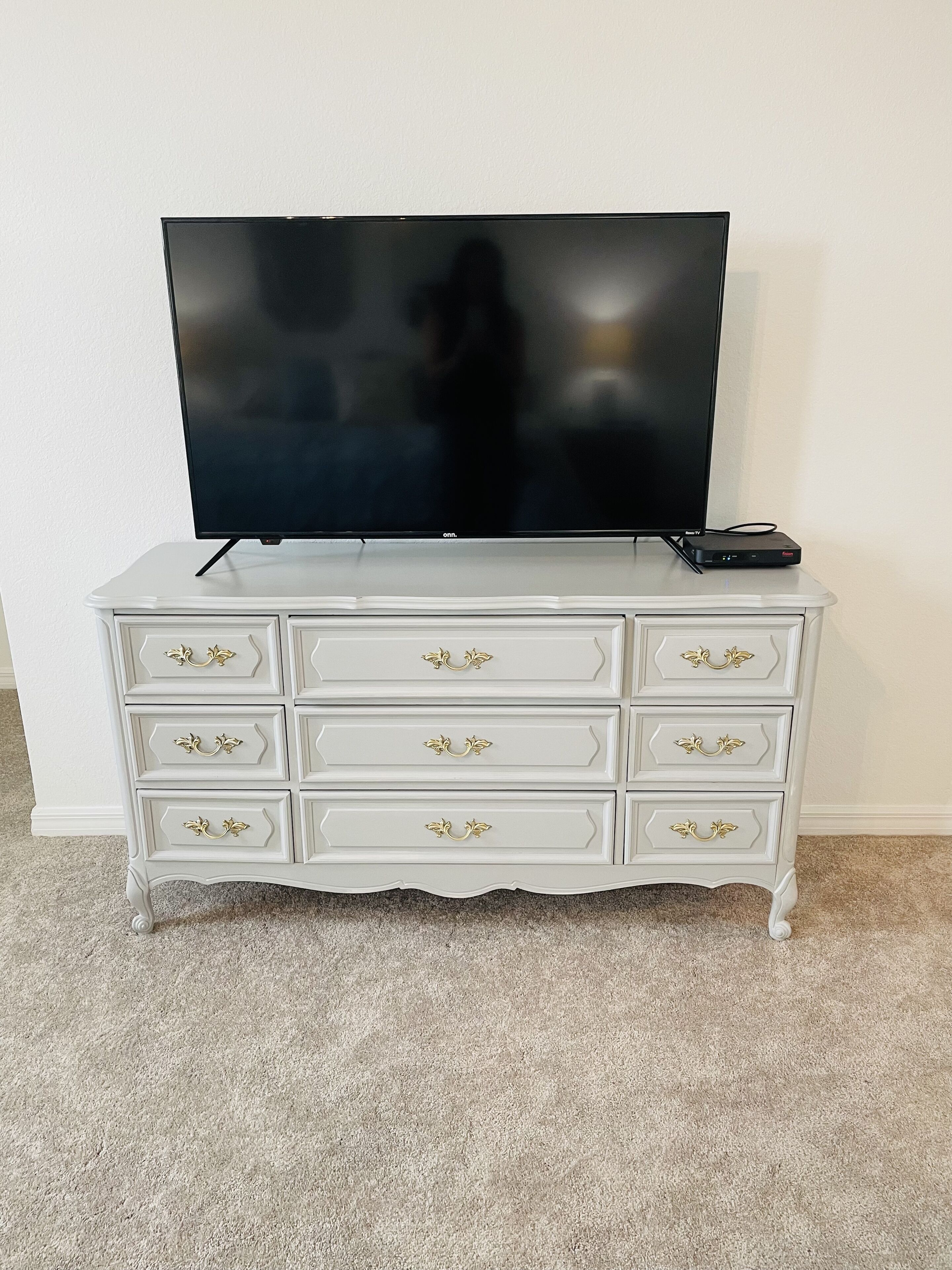 A white dresser with six drawers and a flat-screen TV on top.