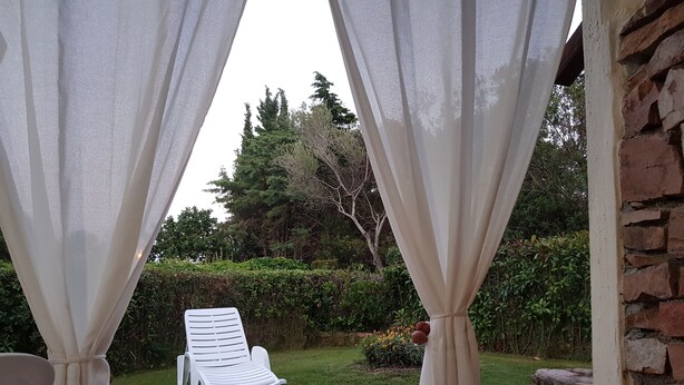Un fauteuil de jardin blanc, placé dans un jardin avec un mur de briques et de la verdure en arrière-plan.