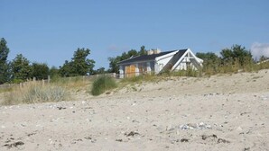 A house on a sandy beach with a clear sky. - Strandhaus-Fehmarn, port side, sea view and beach on the doorstep (Fehmarn)