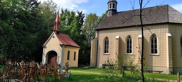 A church with a red steeple and a bell tower, surrounded by a cemetery with wooden crosses. - 🌞FeWo Berger, quiet location on the outskirts of Frauenzell, near Center Parcs in the Allgäu (Altusried - Frauenzell)