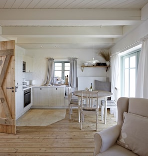 Un'ampia cucina con isola centrale, pavimento in legno e zona pranzo con tavolo rotondo e sedie.