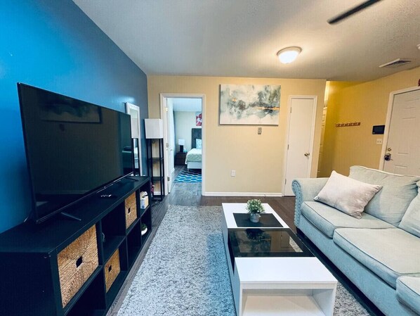 A living room with a TV, sofa, coffee table, and a bookshelf.