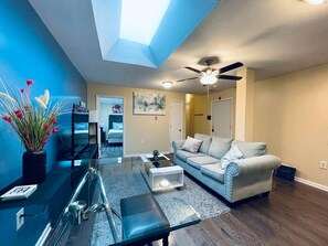 A modern living room with a sofa, coffee table, and a dining area with a glass table.