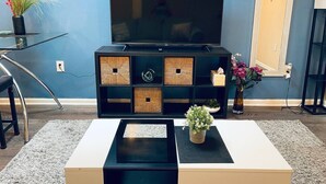 A living room with a flat-screen TV, a coffee table, and a TV stand with storage boxes. - Cozy 1BD Apt @Magic Garden in Center City (Philadelphia)