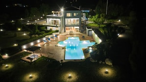 Un hôtel moderne doté d’une piscine, d’un espace extérieur aménagé et de chemins bien éclairés.