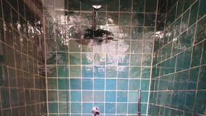A small, tiled shower stall with a handheld showerhead and a wall-mounted faucet. - Apartment for couples and artisans (Ehingen (Donau))