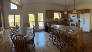 A spacious kitchen with wooden cabinets, a large island with bar stools, and a dining area with a long table and chairs.