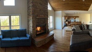 A spacious living room with a stone fireplace, a large sectional sofa, and a blue armchair.