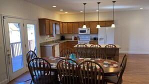 A modern kitchen with wooden cabinets, a central island, and a dining area with a wooden table and chairs.