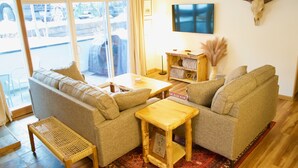 Ein Wohnzimmer mit zwei Sofas, einem Holztisch und einem an der Wand befestigten Fernseher.