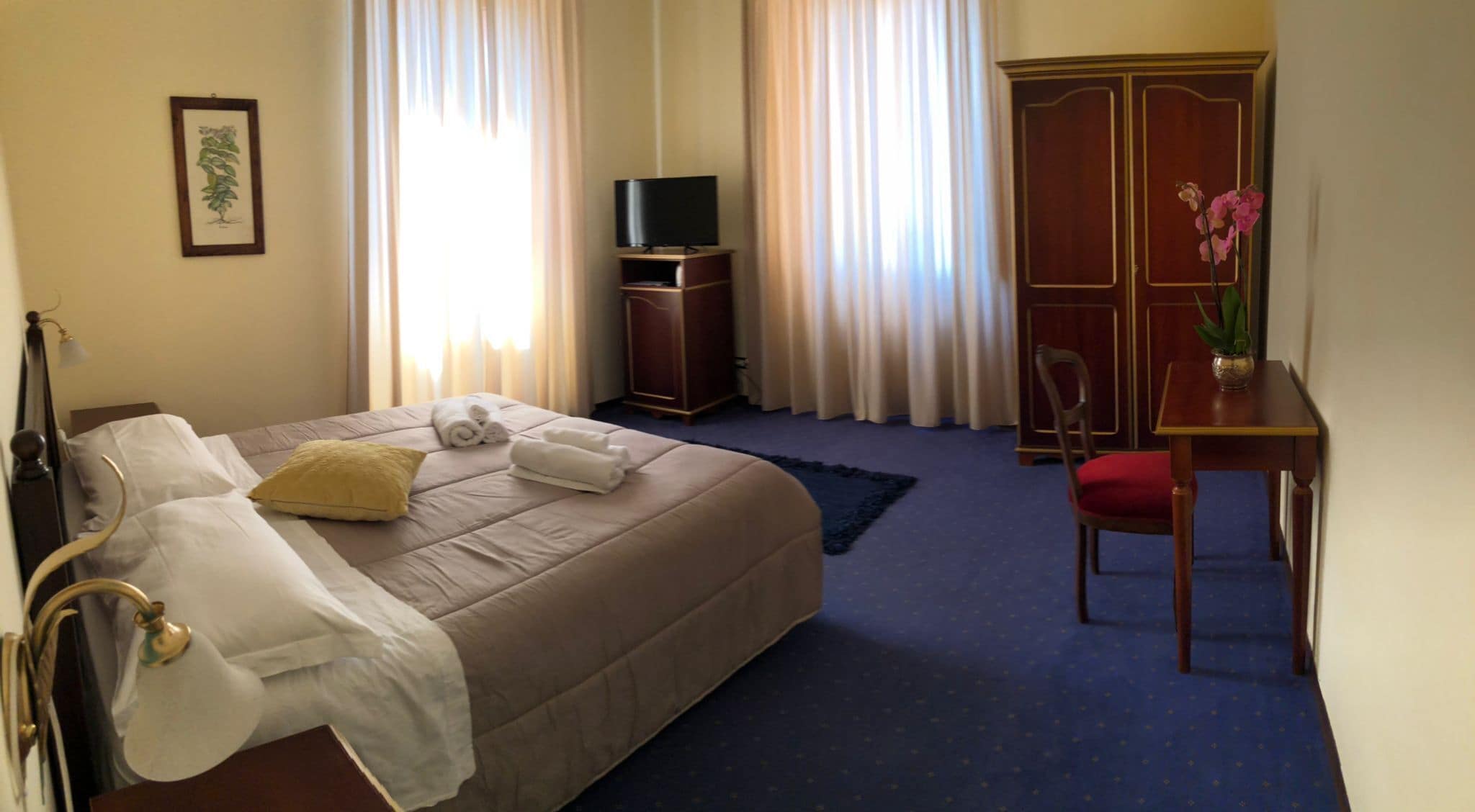 Ein Hotelzimmer mit einem Bett, einem Schreibtisch, einem Fernseher und einem Kleiderschrank.