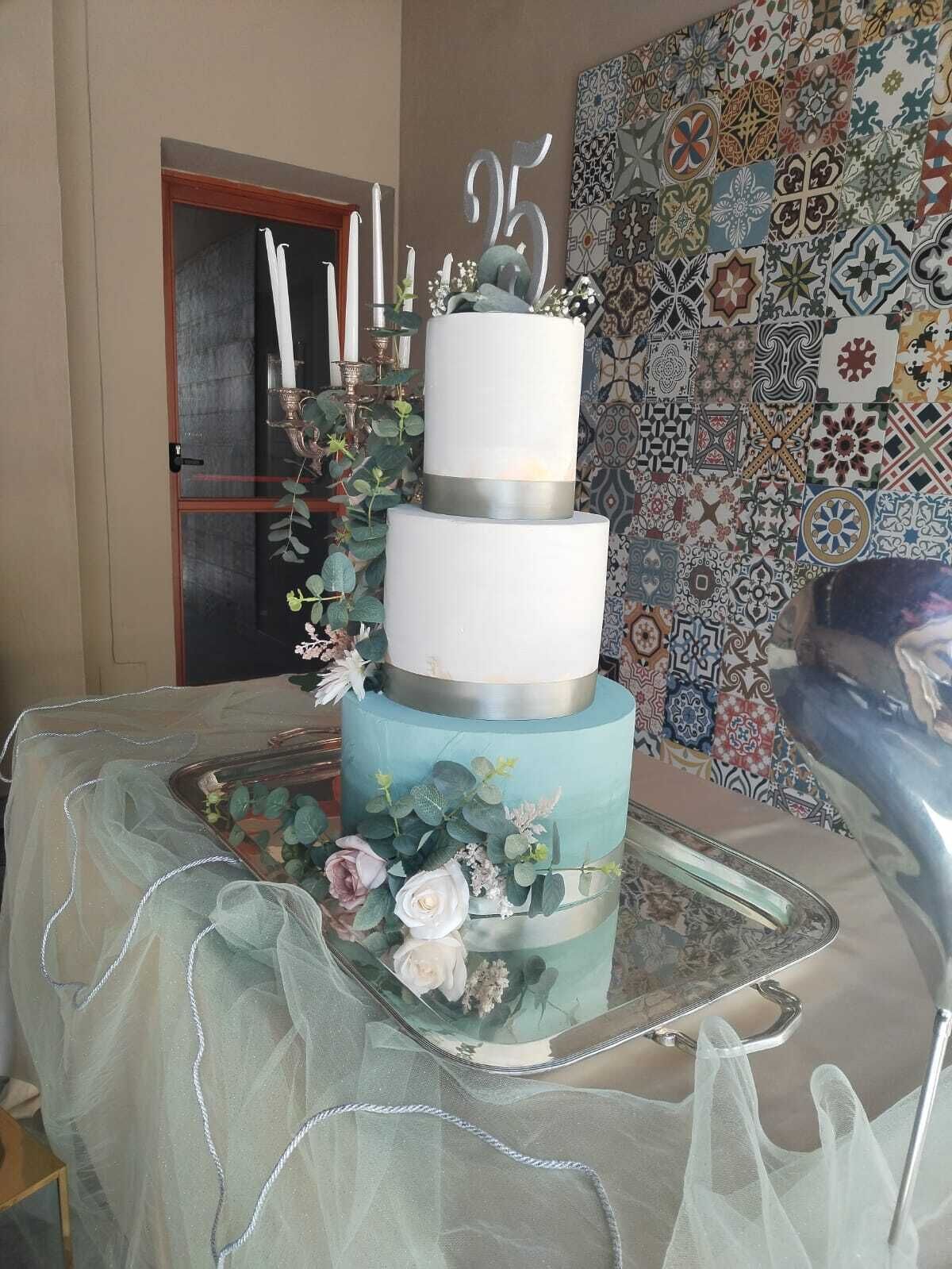 Ein mehrstöckiger Kuchen mit floralen Verzierungen auf einem Tisch, vor einer Wand mit Muster.