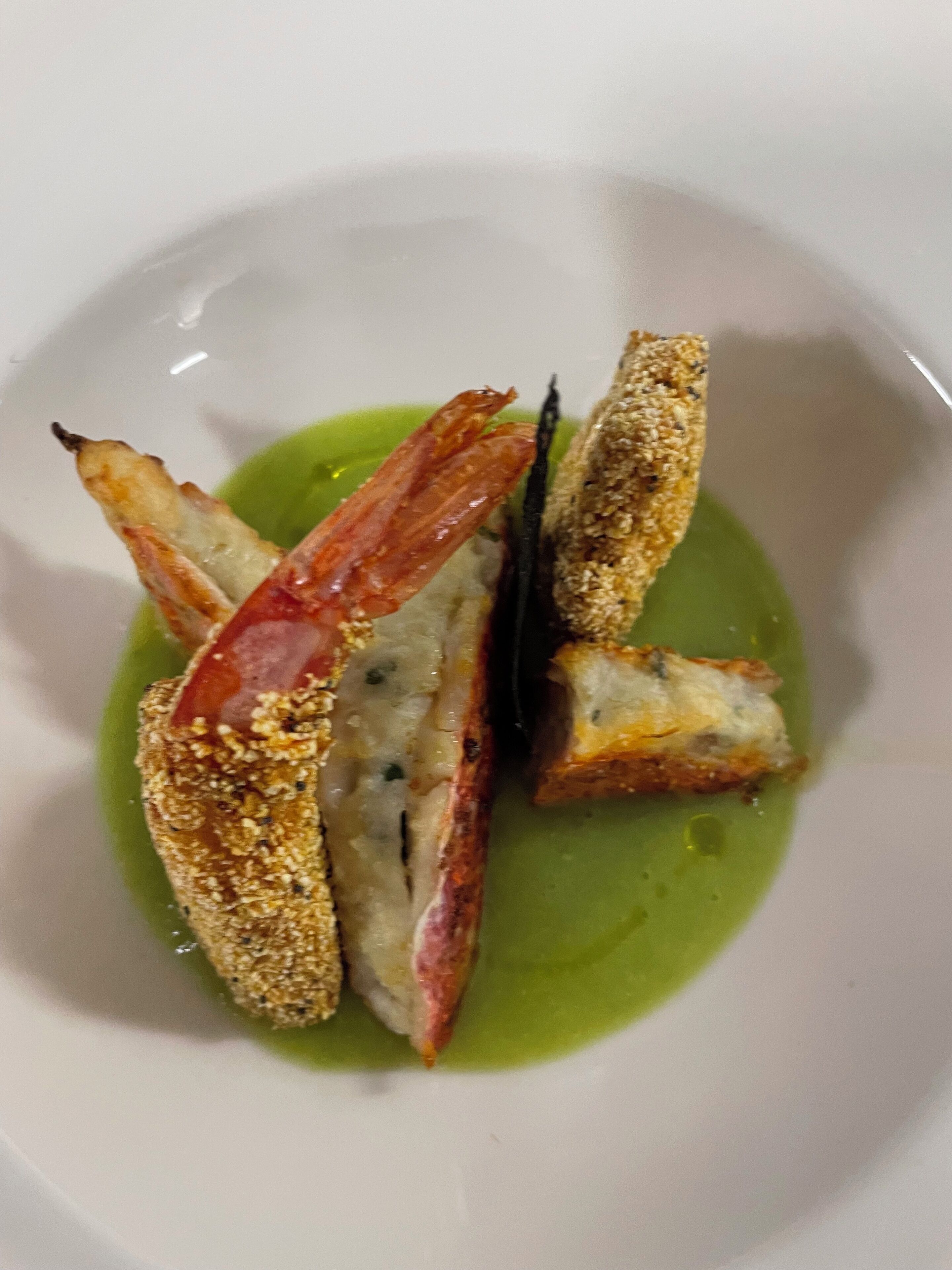 Un plato con porciones de comida rebozada y frita, posiblemente pollo, servido sobre una fuente blanca con salsa verde.