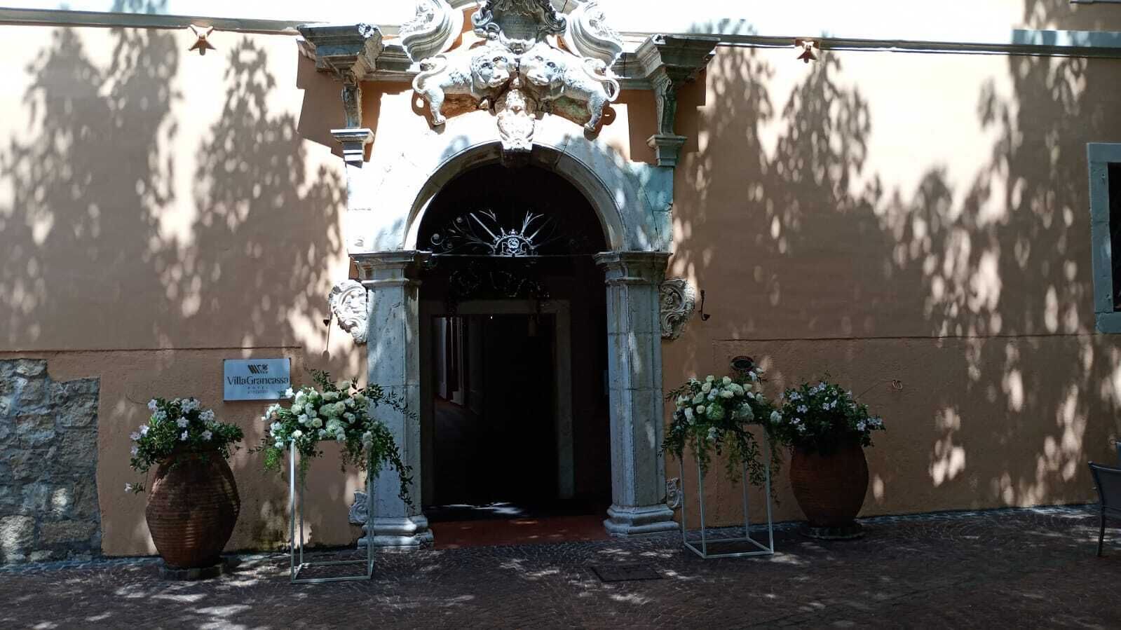 VillaGrancaccia entrance with ornate columns and a dark doorway, surrounded by potted plants.