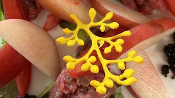 Une assiette contenant un plat à base de viande, des légumes et un élément décoratif jaune.