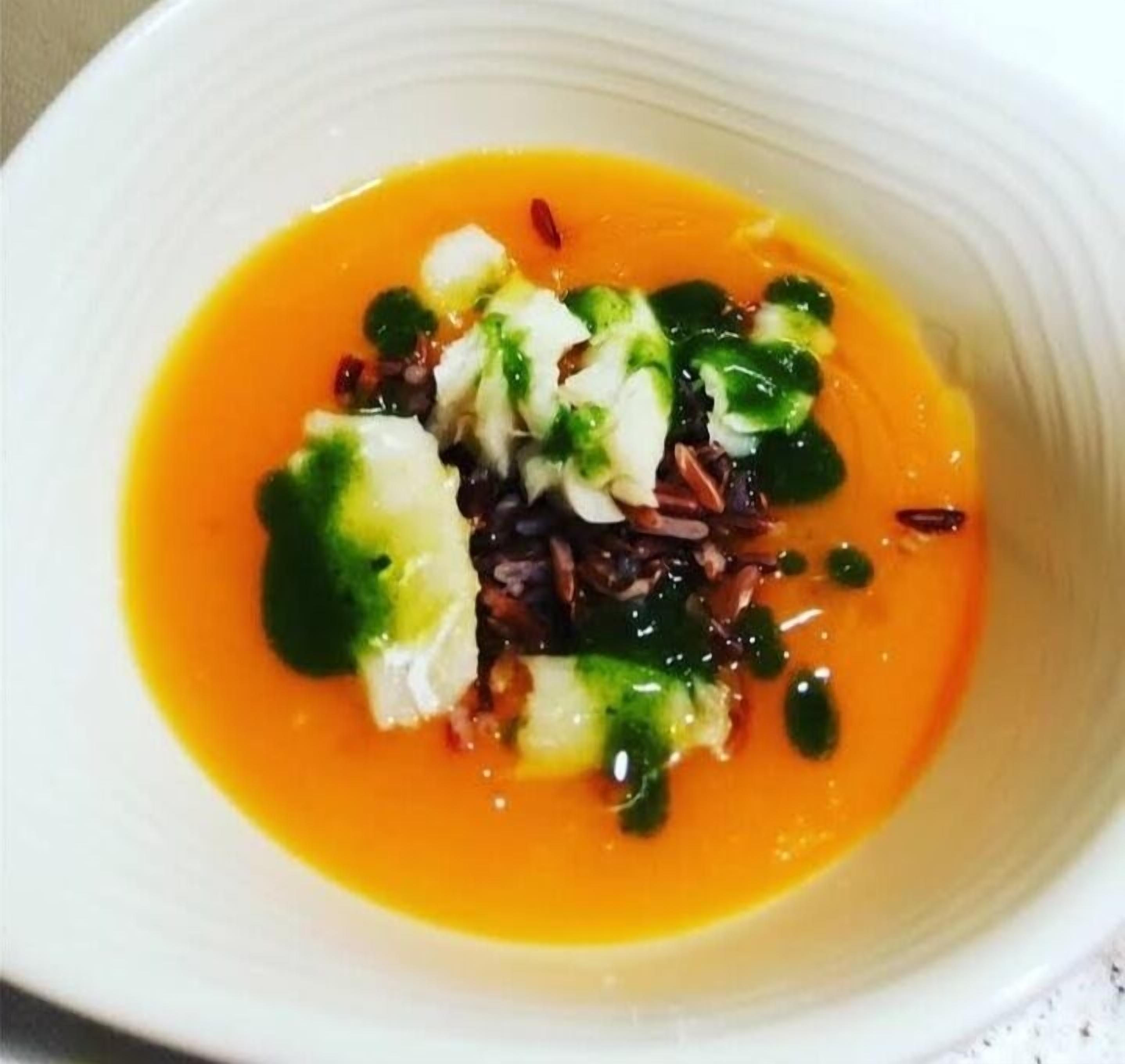 Un plato de sopa con una base cremosa y color naranja intenso.