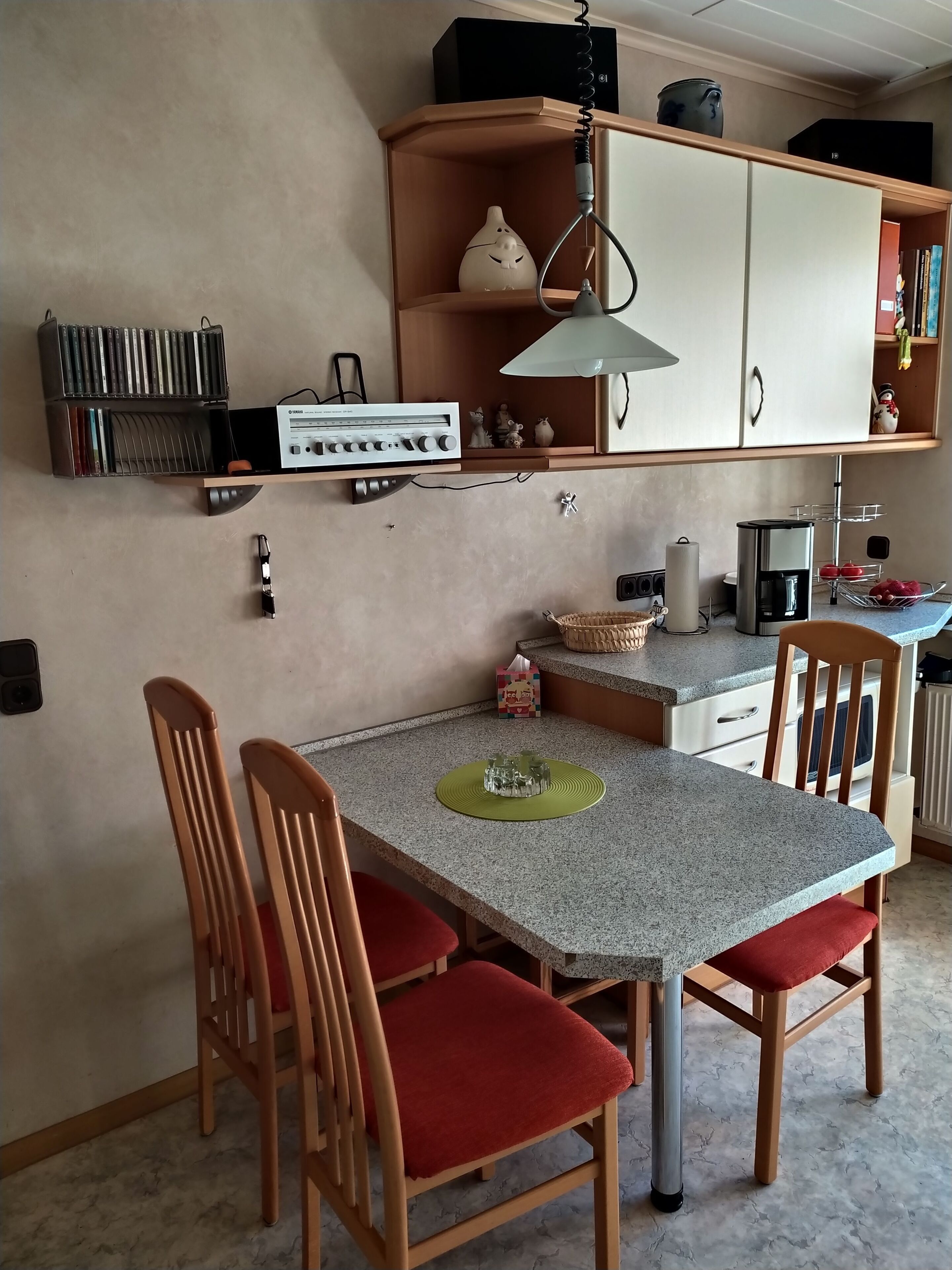 A compact kitchen with a dining table, chairs, and a coffee machine.