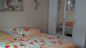 Un dormitorio con cama, armario y espejo adosado a la pared.