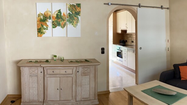 Cocina moderna con armarios de madera y una zona de comedor con mesa y banco.