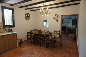 A dining area with a wooden table and chairs, a chandelier, and a window with a decorative metal grill.
