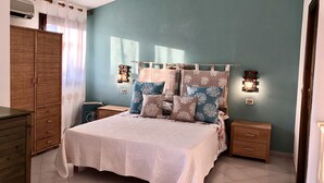 Un dormitorio con cama, mesitas de noche, armario y aire acondicionado instalado en la pared.