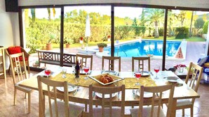 Un espace repas offrant une vue sur une piscine, avec des meubles d’extérieur et une table mise pour le repas.