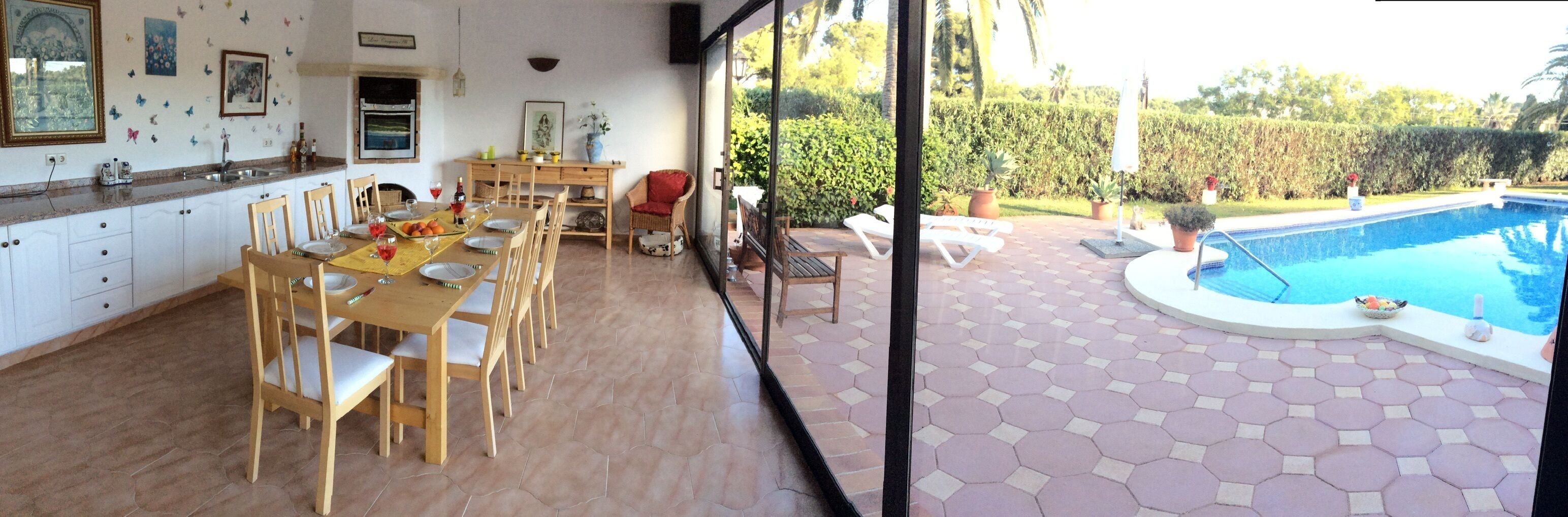 Une cuisine avec des meubles blancs et un coin repas comprenant des chaises en bois et une table dressée pour quatre personnes.