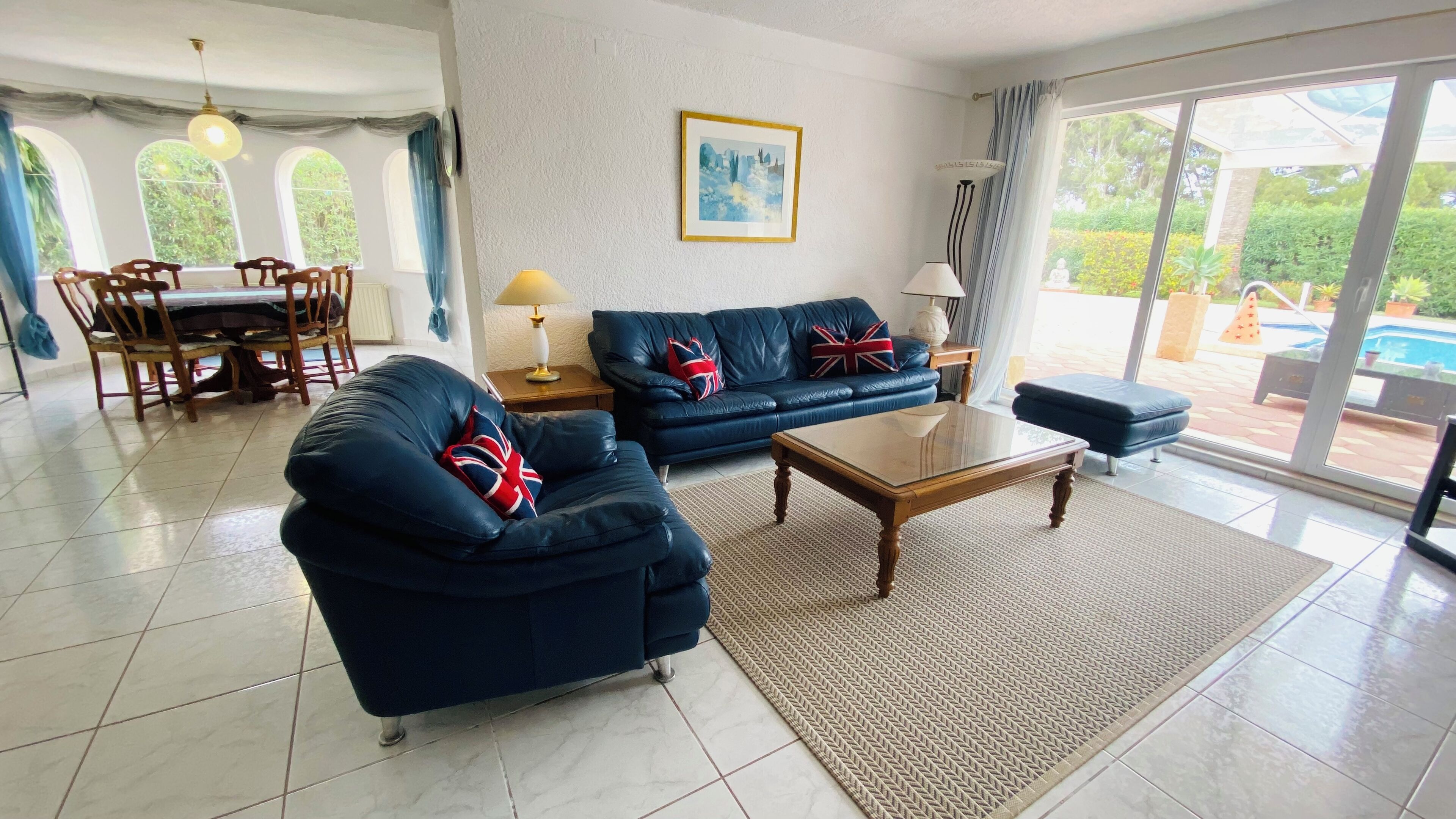 Een woonkamer met een blauwe bank, een salontafel en een eethoek met houten stoelen en een tafel.