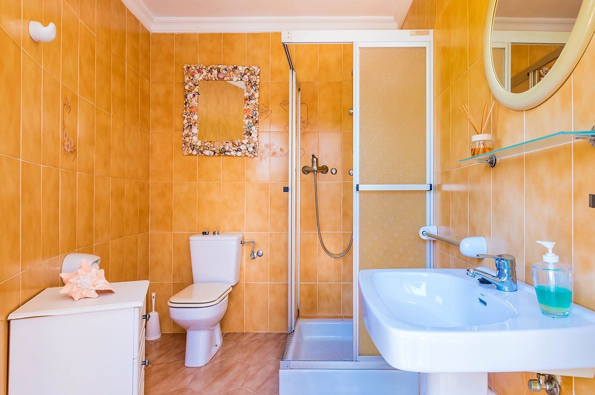 Un baño con inodoro, ducha, lavamanos y espejo.