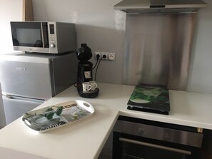 Eine Küchenzeile mit Mikrowelle, Kaffeemaschine und Kühlschrank.