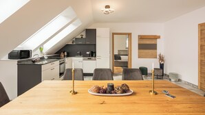 A modern kitchen with a skylight, a dining area with a wooden table, and a view of the adjacent living space. - Fantastic luxury apartment in Salzburg's ski paradise (Mauterndorf)