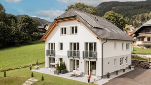A modern two-story house with a balcony, a lawn, and a mountain backdrop. - Fantastic luxury apartment in Salzburg's ski paradise (Mauterndorf)