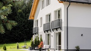 A modern two-story house with a balcony, a patio with outdoor furniture, and a well-maintained garden. - Fantastic luxury apartment in Salzburg's ski paradise (Mauterndorf)